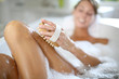 Woman in bathtub scrubbing her legs