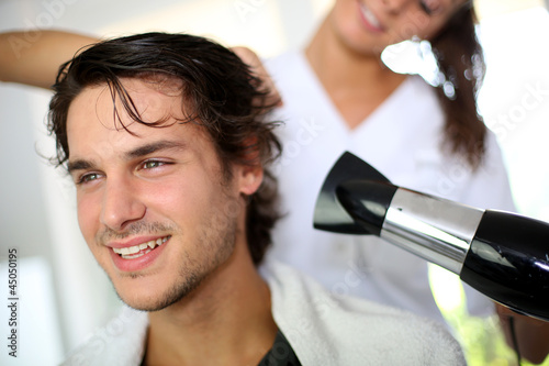 Photo: Young man in beauty salon having his hair dried Young man in beauty salon having his hair dried