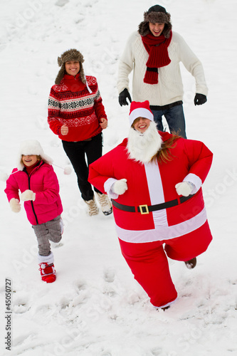 Photo: Chasing Santa Claus - happy family enjoying Christmas Chasing Santa Claus - happy family enjoying Christmas