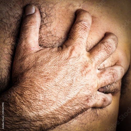 Photo: Hand grabbing the chest of a man who is suffering a heart attack Hand grabbing the chest of a man who is suffering a heart attack