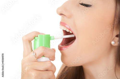 Photo: suffering from pain, young woman using throat spray suffering from pain, young woman using throat spray