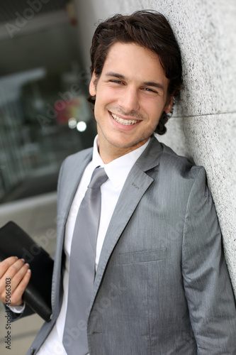 Photo: Closeup of young businessman leaning on wall Closeup of young businessman leaning on wall