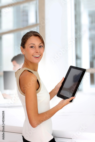 Photo: Businesswoman standing in office with digital tablet Businesswoman standing in office with digital tablet