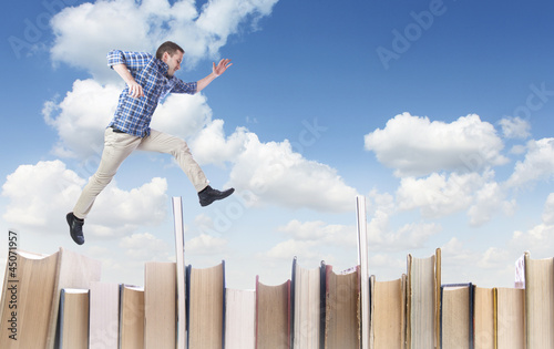 Photo: Man jumping over books Man jumping over books
