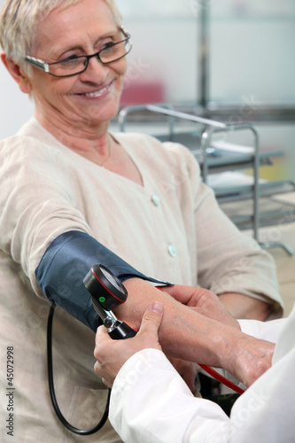 Photo: a nurse taking blood pressure of a smiling senior woman a nurse taking blood pressure of a smiling senior woman