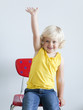"Girl (2-3) girl sitting on chair and raising hand, studio shot"