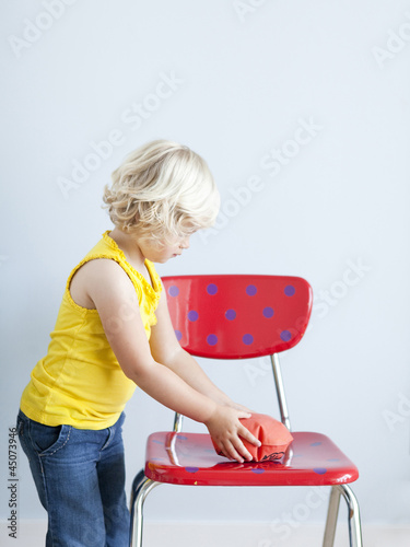 Photo: "Girl (2-3) putting whoopie cushion on chair, studio shot" "Girl (2-3) putting whoopie cushion on chair, studio shot"