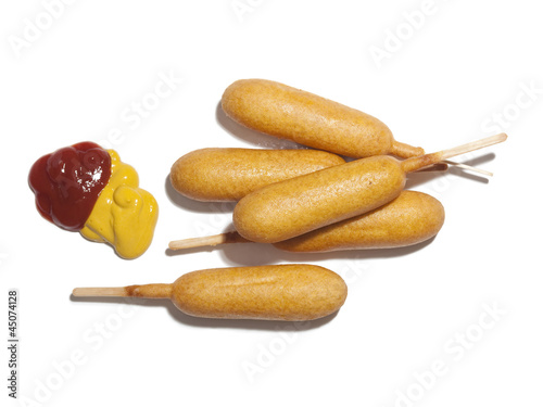 Photo: "Corndogs with ketchup and mustard, view from above, studio shot" "Corndogs with ketchup and mustard, view from above, studio shot"