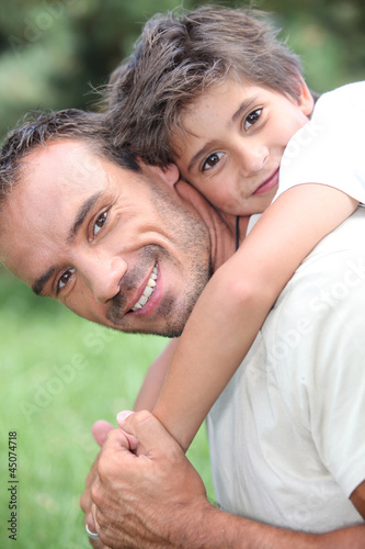 Photo: Father giving son piggy back outdoors Father giving son piggy back outdoors