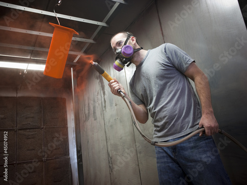 Photo: "USA, Utah, Orem, man using paint spray gun" "USA, Utah, Orem, man using paint spray gun"