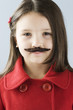 Studio portrait of girl (6-7) wearing fake moustache