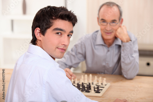 Photo: Young man playing chess with his grandfather Young man playing chess with his grandfather