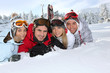 Four young adults laying in the snow