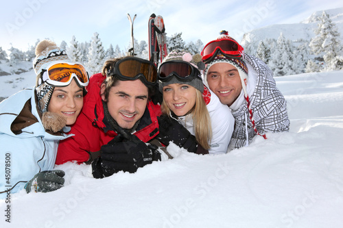 Photo: Four young adults laying in the snow Four young adults laying in the snow