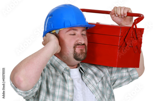 Photo: Construction worker listening sounds of his toolbox Construction worker listening sounds of his toolbox