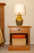 Wood furniture nightstand with lamp and bed.
