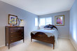 Blue bedroom with dark wood bed and dresser.