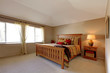 Lagre bedroom with wood bed and nightstand with stipe bedding.