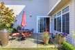 House back yard with terrace with red chairs and umbrella.