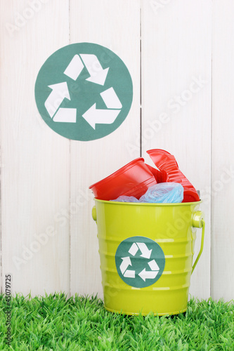 Photo: Recycling bin on green grass near wooden fence Recycling bin on green grass near wooden fence