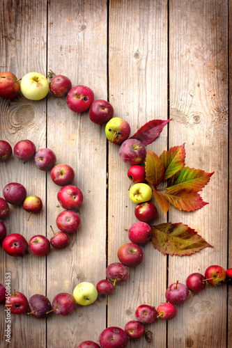 Photo: Autumn apples and leaves on wooden table with grunge texture Autumn apples and leaves on wooden table with grunge texture