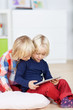 zwei kleine mädchen schauen auf tablet