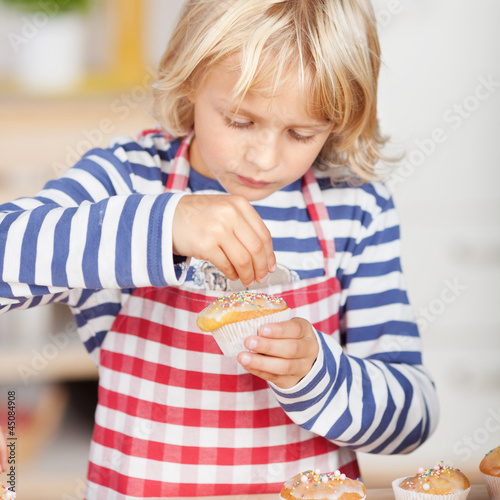 Photo: mädchen verziert törtchen mit schokostreuseln mädchen verziert törtchen mit schokostreuseln