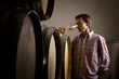 Winemaker in cellar smelling white wine in glass.