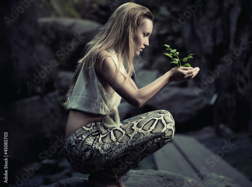 Photo: Beautiful young woman holding a plant Beautiful young woman holding a plant