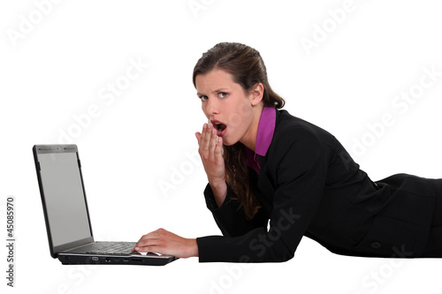 Photo: Bored woman lying in front of a laptop Bored woman lying in front of a laptop