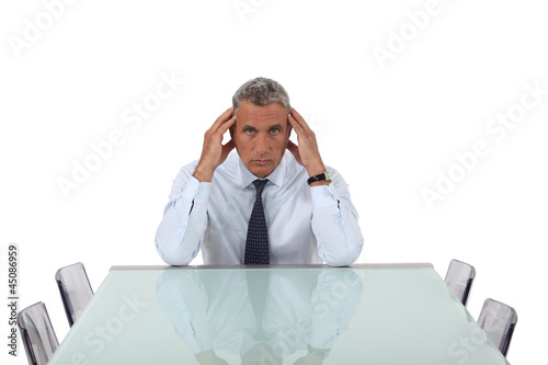 Photo: Stresses senior businessman sat in empty boardroom Stresses senior businessman sat in empty boardroom