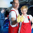 Two car mechanics in garage show thumbs up