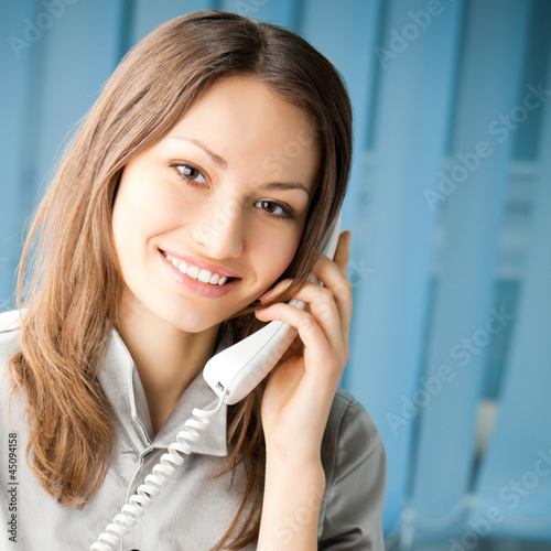 Photo: Young business woman with phone at office Young business woman with phone at office
