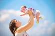Mother raising her little daughter up high