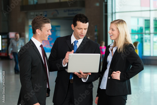 Photo: Redende Business-Gruppe mit Laptop Redende Business-Gruppe mit Laptop