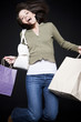 Studio portrait of young woman jumping with shopping bags