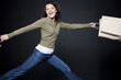 Studio portrait of young woman jumping with shopping bags