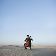 "USA, Utah, Little Sahara, young man with cello in desert"