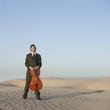 "USA, Utah, Little Sahara, portrait of young man with cello in desert"