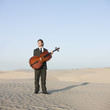 "USA, Utah, Little Sahara, young man with cello in desert"