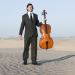"USA, Utah, Little Sahara, portrait of young man with cello in desert"