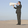 "USA, Utah, Little Sahara, businessman shouting through loud speaker in desert"
