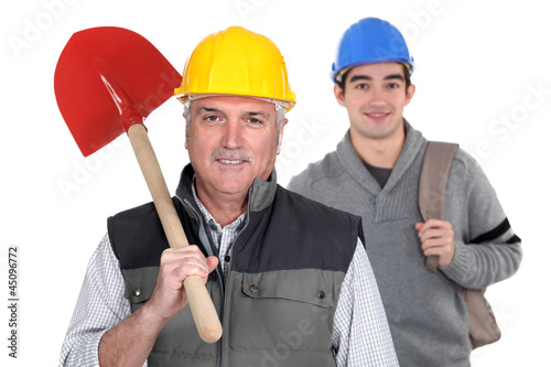 Photo: Experienced tradesman standing in front of his apprentice Experienced tradesman standing in front of his apprentice