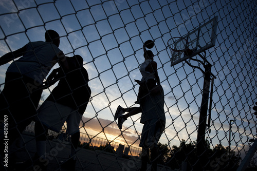 Photo: "USA, Utah, Salt Lake City, four young men playing street basketball, low angle view" "USA, Utah, Salt Lake City, four young men playing street basketball, low angle view"