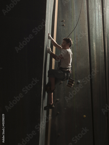 Photo: "USA, Utah, Sandy, boy climbing in indoor climbing gym, side view" "USA, Utah, Sandy, boy climbing in indoor climbing gym, side view"
