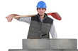 a handsome bricklayer by brickwall holding shovel