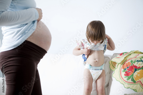 Photo: Girl (2-3) comparing belly with pregnant mother Girl (2-3) comparing belly with pregnant mother