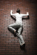 Studio shot of young woman climbing up brick wall