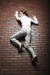 Studio shot of young woman climbing up brick wall