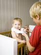 "USA, Utah, Provo, Mother dressing baby boy (18-23 months) in crib"
